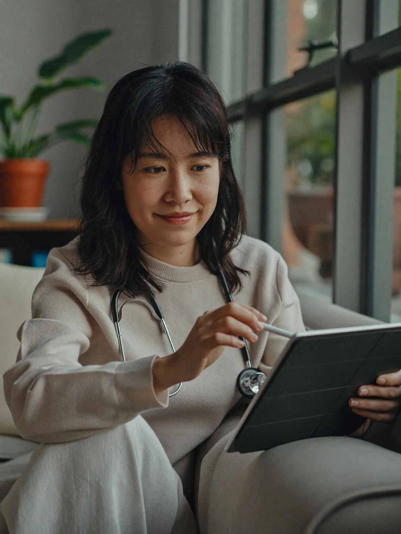 A woman on a sofa holding a tablet during a video visit